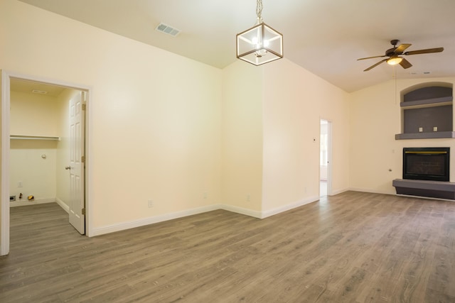 7113 Avignon Ct NW, Albuquerque, NM 87114 - unfurnished living room featuring a glass covered fireplace, wood finished floors, lofted ceiling, a ceiling fan, and baseboards