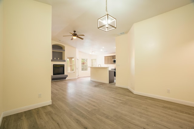 7113 Avignon Ct NW, Albuquerque, NM 87114 - unfurnished living room with ceiling fan, baseboards, light wood-style floors, a glass covered fireplace, and vaulted ceiling