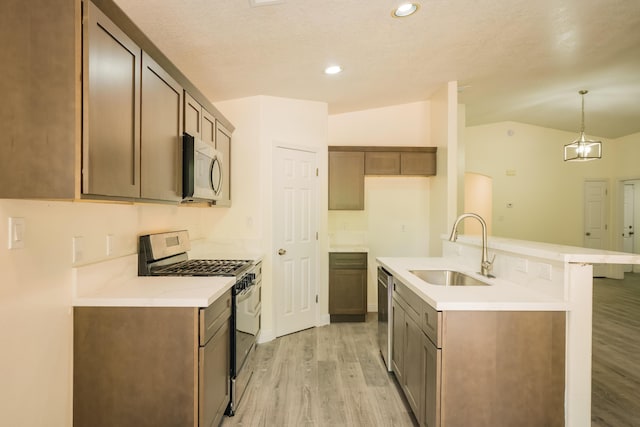 7113 Avignon Ct NW, Albuquerque, NM 87114 - kitchen featuring appliances with stainless steel finishes, a sink, light wood-style flooring, vaulted ceiling, and light countertops