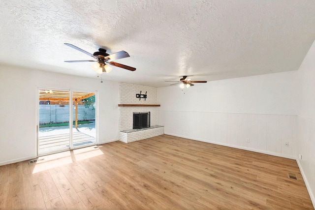 2912 Alcazar St NE, Albuquerque, NM 87110 - unfurnished living room with a ceiling fan, light wood-style floors, a textured ceiling, a brick fireplace, and baseboards