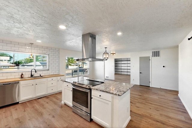 2912 Alcazar St NE, Albuquerque, NM 87110 - kitchen with stainless steel appliances, island exhaust hood, a sink, white cabinets, and decorative backsplash