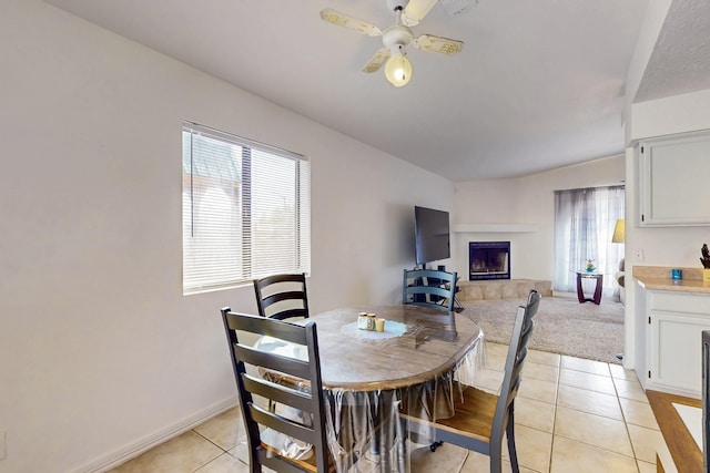 402 Calle Don Santiago NE, Los Lunas, NM 87031 - dining space with light tile patterned flooring, a tile fireplace, a ceiling fan, and baseboards