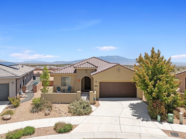 6413 Kings Cyn NE, Rio Rancho, NM 87144 - mediterranean / spanish house with stucco siding, a fenced front yard, an attached garage, driveway, and a tile roof