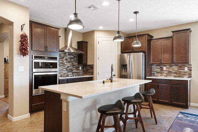 6413 Kings Cyn NE, Rio Rancho, NM 87144 - kitchen featuring appliances with stainless steel finishes, wall chimney range hood, a sink, arched walkways, and light tile patterned floors