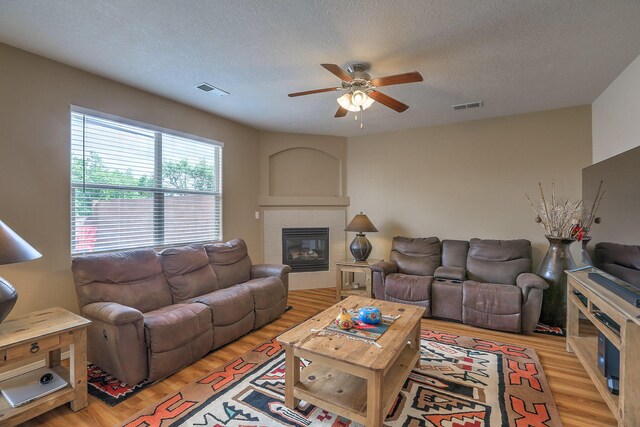 1921 Cortina Loop SE, Rio Rancho, NM 87124 - living area with a ceiling fan, a tile fireplace, light wood-type flooring, and a textured ceiling