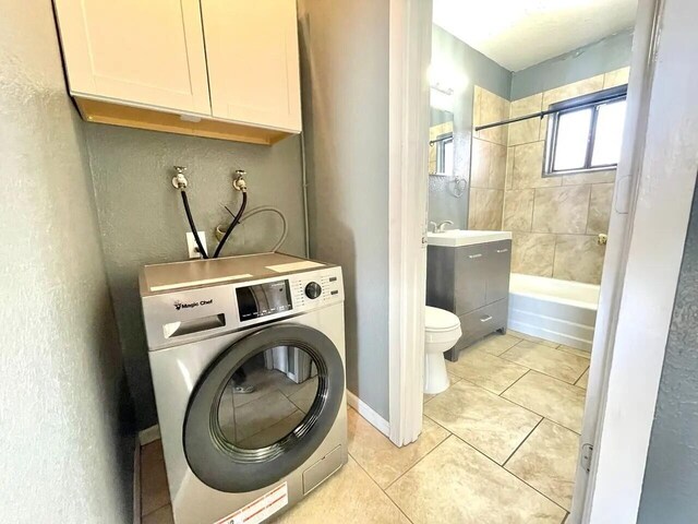 820 Apache Ave NW, Albuquerque, NM 87102 - washroom with washer / clothes dryer, light tile patterned floors, cabinet space, and a textured wall