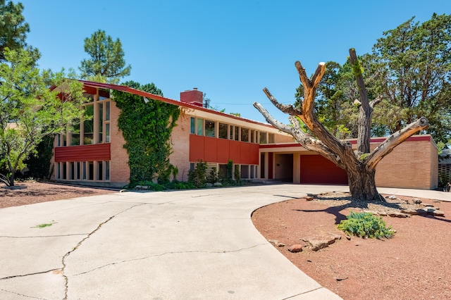 4818 Royene Ave NE, Albuquerque, NM 87110 - view of front of property with brick siding, a chimney, concrete driveway, and a garage