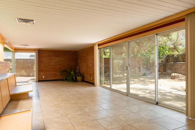 4818 Royene Ave NE, Albuquerque, NM 87110 - unfurnished sunroom with tile patterned floors and brick wall