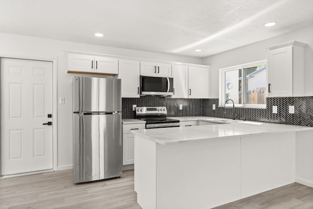 7525 Gill St NE, Albuquerque, NM 87109 - kitchen featuring appliances with stainless steel finishes, white cabinetry, a peninsula, tasteful backsplash, and recessed lighting