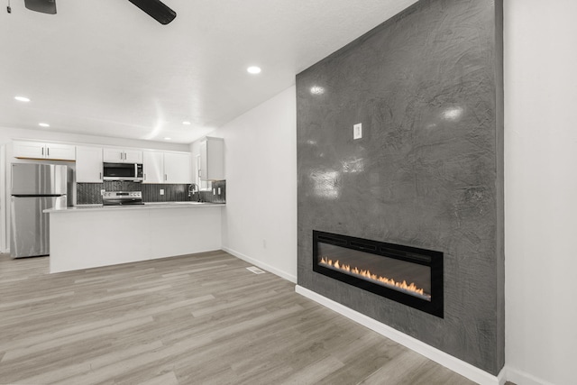 7525 Gill St NE, Albuquerque, NM 87109 - unfurnished living room featuring a large fireplace, light wood-style floors, recessed lighting, baseboards, and ceiling fan