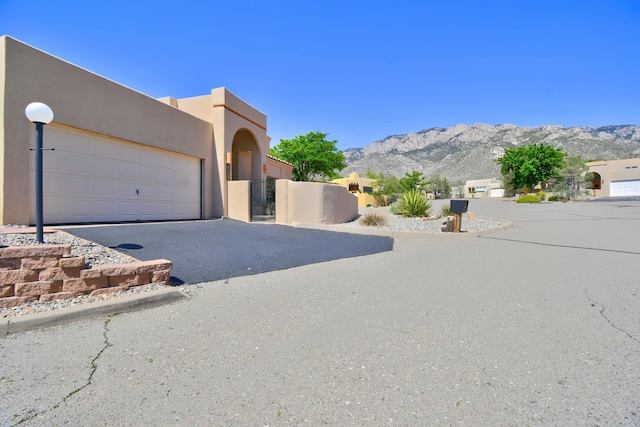 2865 Tramway Cir NE, Albuquerque, NM 87122 - pueblo revival-style home with asphalt driveway, stucco siding, a mountain view, a garage, and a gate