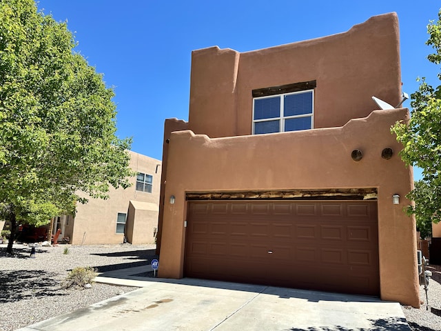 3032 Cochiti St NE, Rio Rancho, NM 87144 - pueblo-style home featuring an attached garage, stucco siding, and concrete driveway