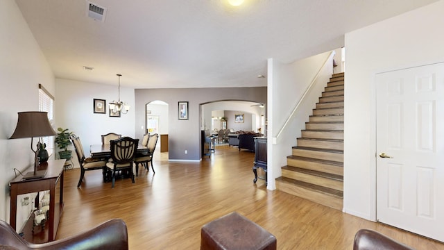 3032 Cochiti St NE, Rio Rancho, NM 87144 - living area with arched walkways, stairs, light wood-type flooring, a chandelier, and baseboards
