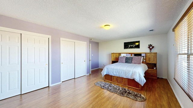 3032 Cochiti St NE, Rio Rancho, NM 87144 - bedroom featuring wood finished floors, multiple closets, baseboards, and a textured ceiling