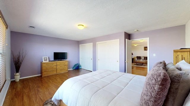 3032 Cochiti St NE, Rio Rancho, NM 87144 - bedroom with wood finished floors, two closets, and baseboards