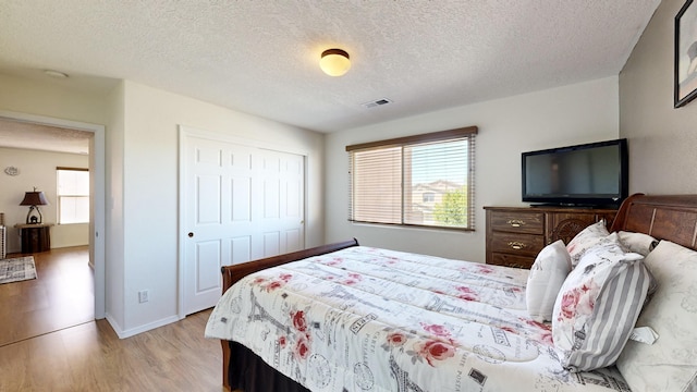 3032 Cochiti St NE, Rio Rancho, NM 87144 - bedroom with light wood finished floors, a textured ceiling, and a closet