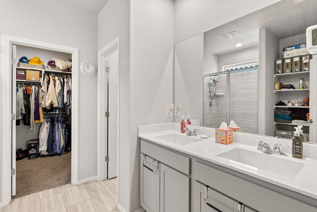 684 Turmalina Dr SE, Rio Rancho, NM 87124 - bathroom featuring double vanity, a shower stall, a textured ceiling, and a spacious closet