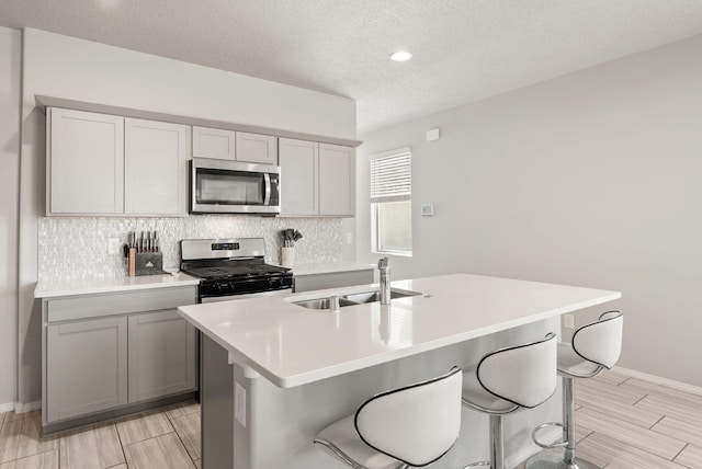 684 Turmalina Dr SE, Rio Rancho, NM 87124 - kitchen with stainless steel appliances, a sink, decorative backsplash, gray cabinetry, and light countertops