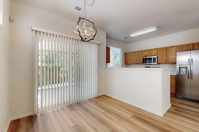 6501 San Antonio Dr NE Unit 2702, Albuquerque, NM 87109 - kitchen featuring stainless steel appliances, light wood-style flooring, brown cabinetry, a chandelier, and light countertops