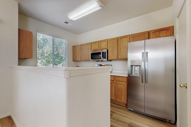 6501 San Antonio Dr NE Unit 2702, Albuquerque, NM 87109 - kitchen with appliances with stainless steel finishes, light wood-type flooring, light countertops, and a peninsula