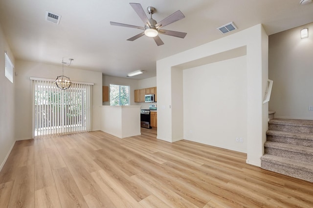6501 San Antonio Dr NE Unit 2702, Albuquerque, NM 87109 - unfurnished living room featuring light wood finished floors, a chandelier, stairway, a ceiling fan, and baseboards