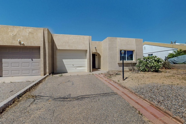 791 Stallion Rd SE, Rio Rancho, NM 87124 - adobe home with stucco siding, an attached garage, and asphalt driveway