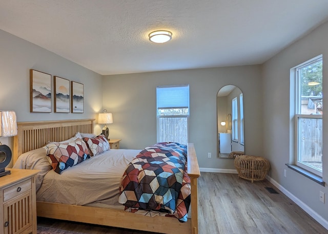 10031 Guadalupe Trl NW Unit A, Albuquerque, NM 87114 - bedroom featuring wood finished floors, arched walkways, and baseboards