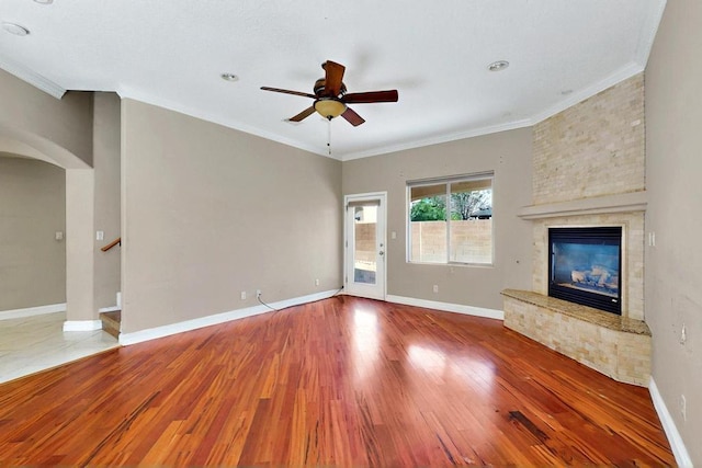 6505 Basket Weaver Ave NW, Albuquerque, NM 87114 - unfurnished living room featuring a ceiling fan, wood finished floors, arched walkways, crown molding, and a large fireplace