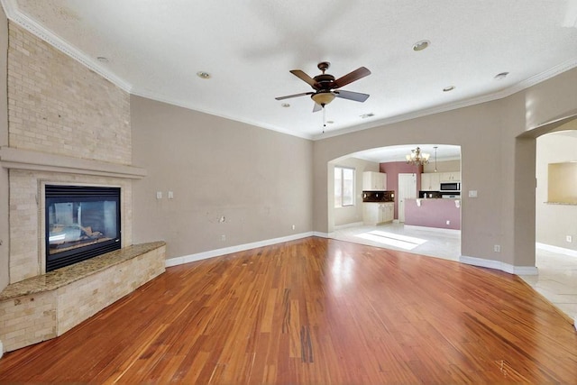 6505 Basket Weaver Ave NW, Albuquerque, NM 87114 - unfurnished living room with wood finished floors, arched walkways, a brick fireplace, a chandelier, and ceiling fan