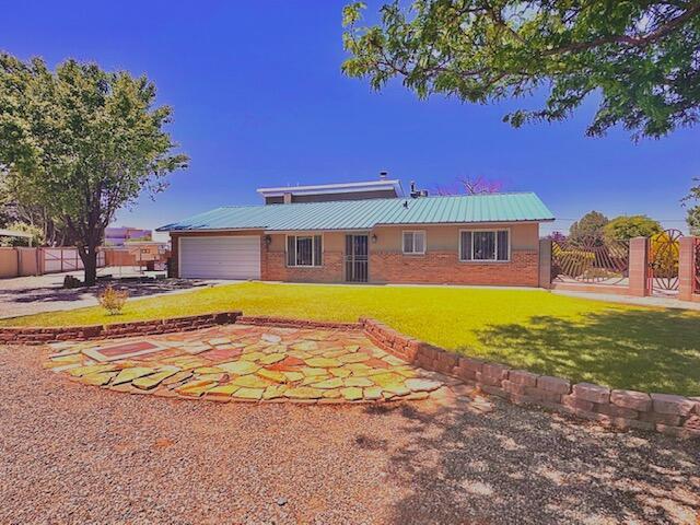 2119 Besler Ln SW, Albuquerque, NM 87105 - rear view of house featuring an attached garage, brick siding, and metal roof