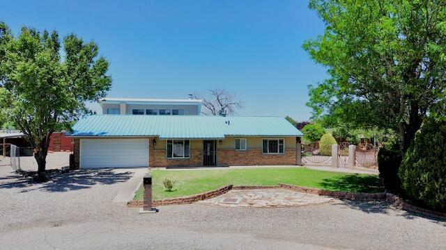 2119 Besler Ln SW, Albuquerque, NM 87105 - view of front facade featuring a front yard, metal roof, an attached garage, and brick siding