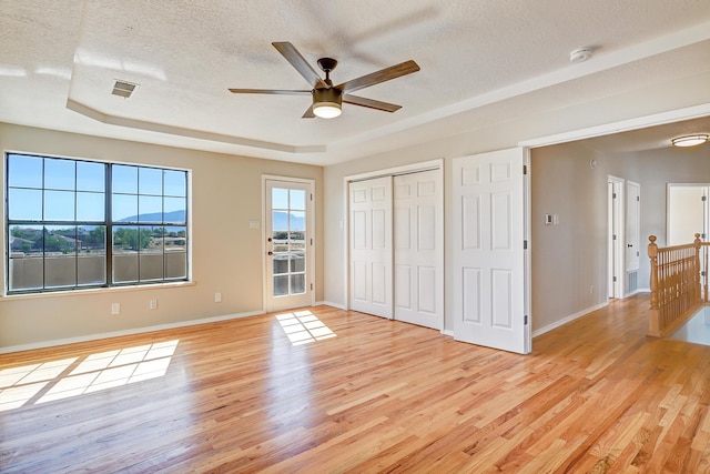 564 Nicklaus Dr SE, Rio Rancho, NM 87124 - unfurnished bedroom with light wood finished floors, a textured ceiling, a raised ceiling, and baseboards