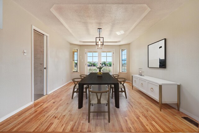 564 Nicklaus Dr SE, Rio Rancho, NM 87124 - dining space with a textured ceiling, light wood-style flooring, baseboards, and a raised ceiling