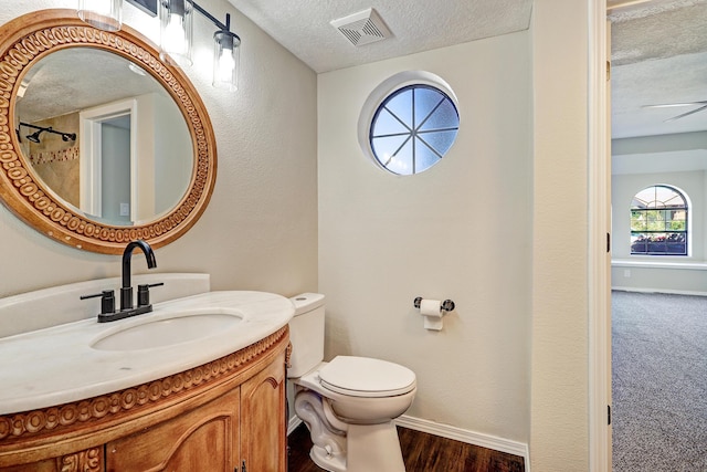 564 Nicklaus Dr SE, Rio Rancho, NM 87124 - full bathroom featuring a textured ceiling, toilet, vanity, baseboards, and a textured wall