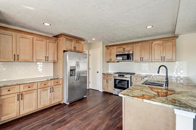 564 Nicklaus Dr SE, Rio Rancho, NM 87124 - kitchen featuring appliances with stainless steel finishes, a sink, a peninsula, dark wood-style flooring, and light stone countertops