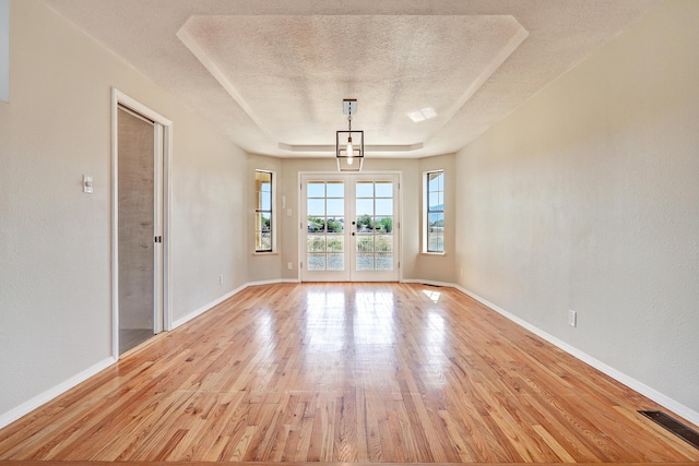 564 Nicklaus Dr SE, Rio Rancho, NM 87124 - unfurnished room with a textured ceiling, light wood finished floors, baseboards, french doors, and a tray ceiling