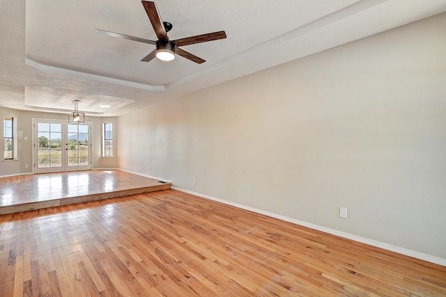 564 Nicklaus Dr SE, Rio Rancho, NM 87124 - unfurnished room with baseboards, light wood finished floors, a raised ceiling, ceiling fan, and a textured ceiling
