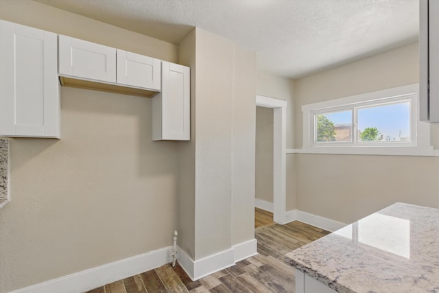 417 8th St NW, Albuquerque, NM 87102 - kitchen with baseboards, wood finished floors, white cabinetry, light stone counters, and a textured ceiling