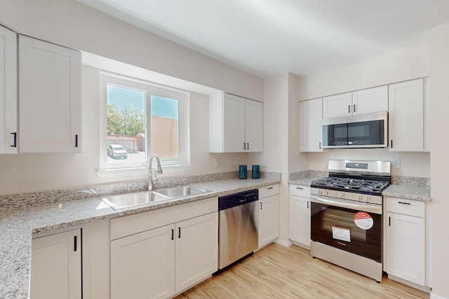1825 Hiawatha Ct NE, Albuquerque, NM 87112 - kitchen with stainless steel appliances, a sink, light wood finished floors, white cabinetry, and light stone countertops