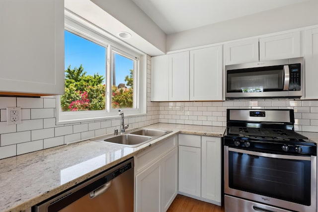 9722 Apache Ave NE, Albuquerque, NM 87112 - kitchen with appliances with stainless steel finishes, a sink, white cabinetry, and decorative backsplash