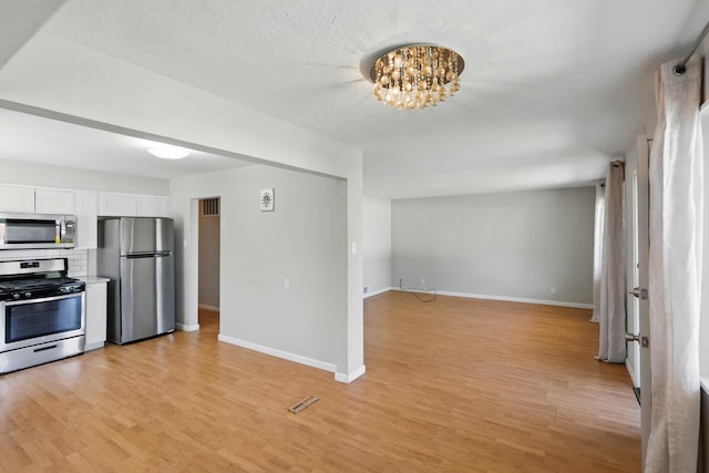 9722 Apache Ave NE, Albuquerque, NM 87112 - kitchen featuring stainless steel appliances, white cabinetry, light wood-style floors, and open floor plan