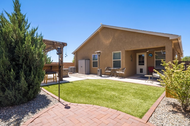 2336 Del Timbre Ln SW, Albuquerque, NM 87121 - back of property with stucco siding, a patio area, ceiling fan, a lawn, and cooling unit