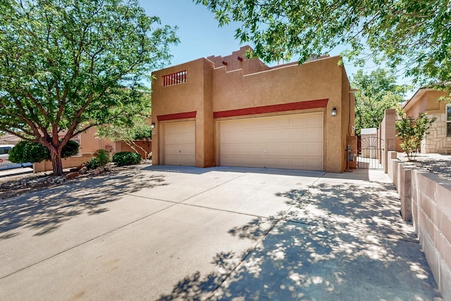 5124 Pyrite Pl NW, Albuquerque, NM 87114 - pueblo-style house with stucco siding, driveway, a gate, and a garage