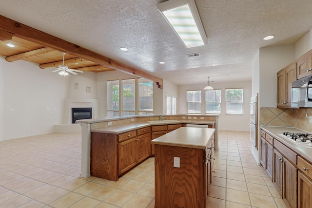 5124 Pyrite Pl NW, Albuquerque, NM 87114 - kitchen featuring a large island, a sink, white appliances, a glass covered fireplace, and decorative backsplash