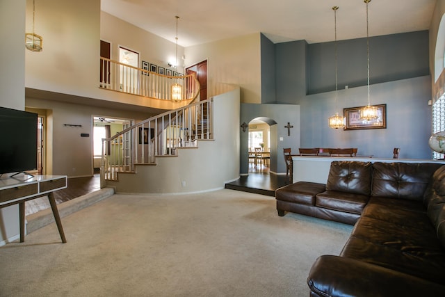8215 Corona Ave NE, Albuquerque, NM 87122 - carpeted living room featuring a high ceiling, a chandelier, arched walkways, stairs, and baseboards