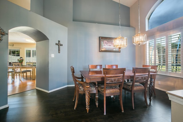 8215 Corona Ave NE, Albuquerque, NM 87122 - dining space with arched walkways, a towering ceiling, dark wood-type flooring, baseboards, and a chandelier