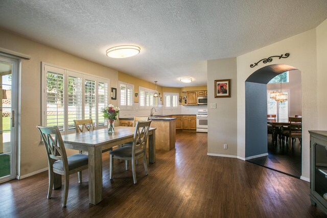 8215 Corona Ave NE, Albuquerque, NM 87122 - dining area with dark wood-style floors, arched walkways, a textured ceiling, and baseboards