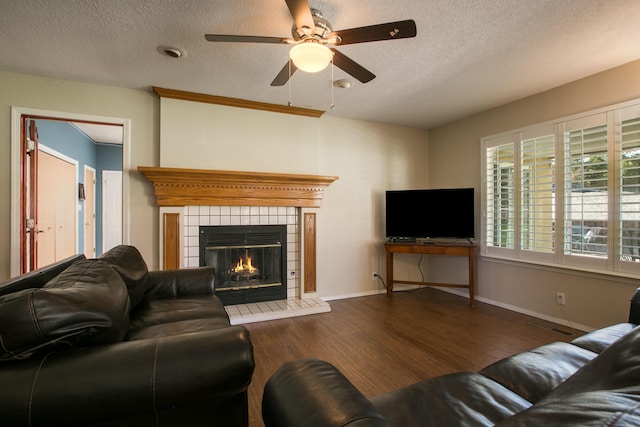 8215 Corona Ave NE, Albuquerque, NM 87122 - living room featuring a ceiling fan, a tiled fireplace, wood finished floors, a textured ceiling, and baseboards