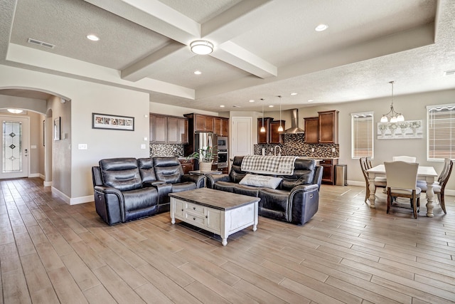 6240 Redroot St, Albuquerque, NM 87120 - living area with arched walkways, baseboards, light wood finished floors, beamed ceiling, and a textured ceiling