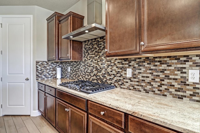 6240 Redroot St, Albuquerque, NM 87120 - kitchen featuring wall chimney range hood, stainless steel gas cooktop, decorative backsplash, and light stone counters